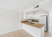 Thumbnail 1 of 14 - A kitchen with white cabinets and a wooden island.