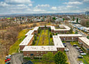 Thumbnail 22 of 25 - A large building complex with a parking lot in front.