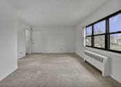 Thumbnail 6 of 25 - Empty room with carpeted floor and large windows.