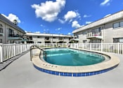 Thumbnail 10 of 12 - A swimming pool in a residential area with buildings in the background.