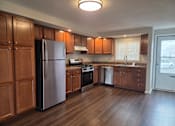 Thumbnail 16 of 17 - A kitchen with wooden cabinets and a refrigerator.
