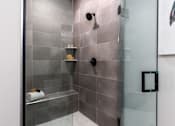 Thumbnail 3 of 38 - Modern bathroom with a glass shower door and grey tiles at Encore at West Valley, White Lake, 48386