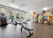 Thumbnail 10 of 32 - a gym with treadmills and other exercise equipment in a building with large windows