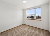 Thumbnail 23 of 25 - A room with a carpeted floor and a window overlooking a landscape.