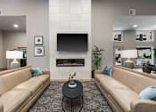 Thumbnail 20 of 66 - A living room with a tan couch, a black coffee table, and a flat screen TV mounted above a fireplace.