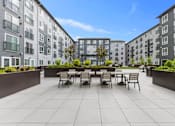 Thumbnail 40 of 66 - A patio with chairs and a table is surrounded by apartment buildings.