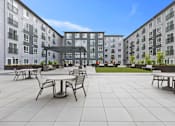 Thumbnail 41 of 66 - A courtyard with tables and chairs surrounded by apartment buildings.