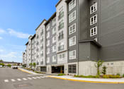 Thumbnail 53 of 66 - A large grey building with a parking lot in front.