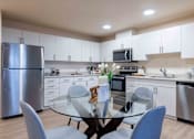 Thumbnail 16 of 32 - A modern kitchen with a glass table and chairs.