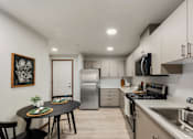 Thumbnail 2 of 21 - A modern kitchen Kendrick Landing, Affordable Housing in Lakewood, WA with a energy efficient appliances round table and chairs, a fridge, a microwave, and a sink.