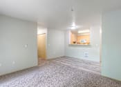 Thumbnail 9 of 15 - A room with a carpeted floor and a small kitchenette in the corner.