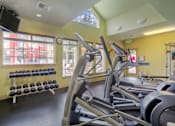 Thumbnail 5 of 15 - A gym with treadmills, dumbbells, and a flat screen TV.