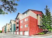 Thumbnail 14 of 15 - A red and beige apartment building with a parking lot in front.