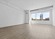 Thumbnail 8 of 46 - an empty living room with a large window and hardwood floors