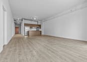 Thumbnail 5 of 46 - an empty living room and kitchen with wood floors and white walls