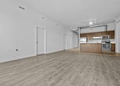 Thumbnail 6 of 46 - an empty living room and kitchen with wood floors and white walls