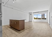 Thumbnail 4 of 46 - an empty living room with a kitchen and a large window