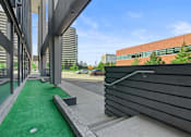 Thumbnail 23 of 46 - a green carpeted patio with a wooden bench next to a building