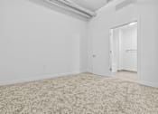 Thumbnail 15 of 46 - a bedroom with white walls and carpet and a door to a closet