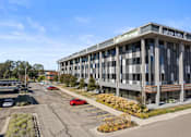 Thumbnail 34 of 46 - a large building with a parking lot in front of it