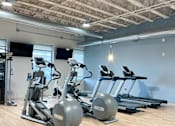 Thumbnail 19 of 46 - a gym with cardio equipment and weights on a wooden floor