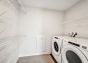 Thumbnail 21 of 43 - a washer and dryer in a laundry room with white walls and white shelves