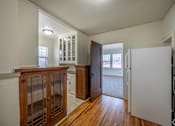 Thumbnail 2 of 27 - A white refrigerator is in a kitchen with wood floors and cabinets.