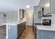 Thumbnail 1 of 31 - A kitchen with a white counter top and wooden floors.