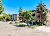 Thumbnail 25 of 30 - A parking lot with cars and apartment buildings in the background.