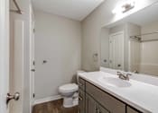 Thumbnail 5 of 31 - A white toilet sits in a small bathroom with a sink and mirror.