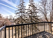 Thumbnail 25 of 35 - A balcony with a black 956 Place Apartments, Forest Lake, MNrailing and a view of a tree and a road.