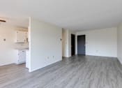 Thumbnail 36 of 41 - A spacious room with a kitchenette and a door leading to another room.