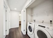Thumbnail 30 of 43 - a washer and dryer in a laundry room with white walls and wood floors