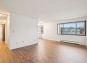 Thumbnail 36 of 37 - A room with wooden floors and a window overlooking a building.