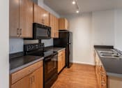 Thumbnail 35 of 39 - A kitchen with wooden cabinets and black appliances.