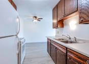 Thumbnail 31 of 35 - A kitchen with a white fridge, wooden cabinets, and a ceiling fan.