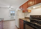 Thumbnail 25 of 37 - A kitchen with a black stove top oven and a white refrigerator.