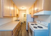 Thumbnail 19 of 34 - A kitchen with a white stove top oven and wooden cabinets.
