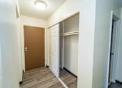 Thumbnail 18 of 34 - A hallway with a brown door and white walls.