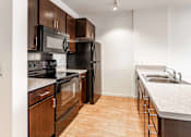 Thumbnail 34 of 39 - A kitchen with black appliances and wooden cabinets.