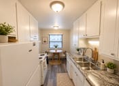 Thumbnail 22 of 23 - A kitchen with white cabinets and a washer and dryer.