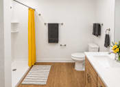 Thumbnail 34 of 35 - A bathroom with a toilet, sink, and yellow shower curtain.
