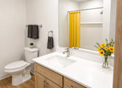Thumbnail 35 of 35 - A white toilet sits next to a sink in a bathroom.
