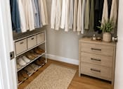 Thumbnail 30 of 35 - A white closet with clothes hanging and drawers underneath.