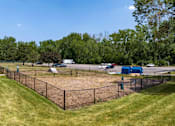 Thumbnail 9 of 34 - A baseball field with a fence and a blue building in the background.