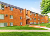 Thumbnail 33 of 34 - A red brick apartment building with green grass in front.