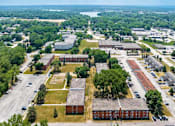 Thumbnail 11 of 34 - A bird's eye view of a campus with buildings, trees, and a parking lot.