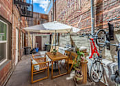 Thumbnail 10 of 12 - A patio with a table and chairs and a bicycle.