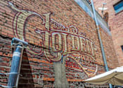Thumbnail 2 of 12 - The Old Shoe's sign is on a brick wall.