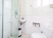 Thumbnail 8 of 12 - A white toilet in a bathroom with a glass shower door.